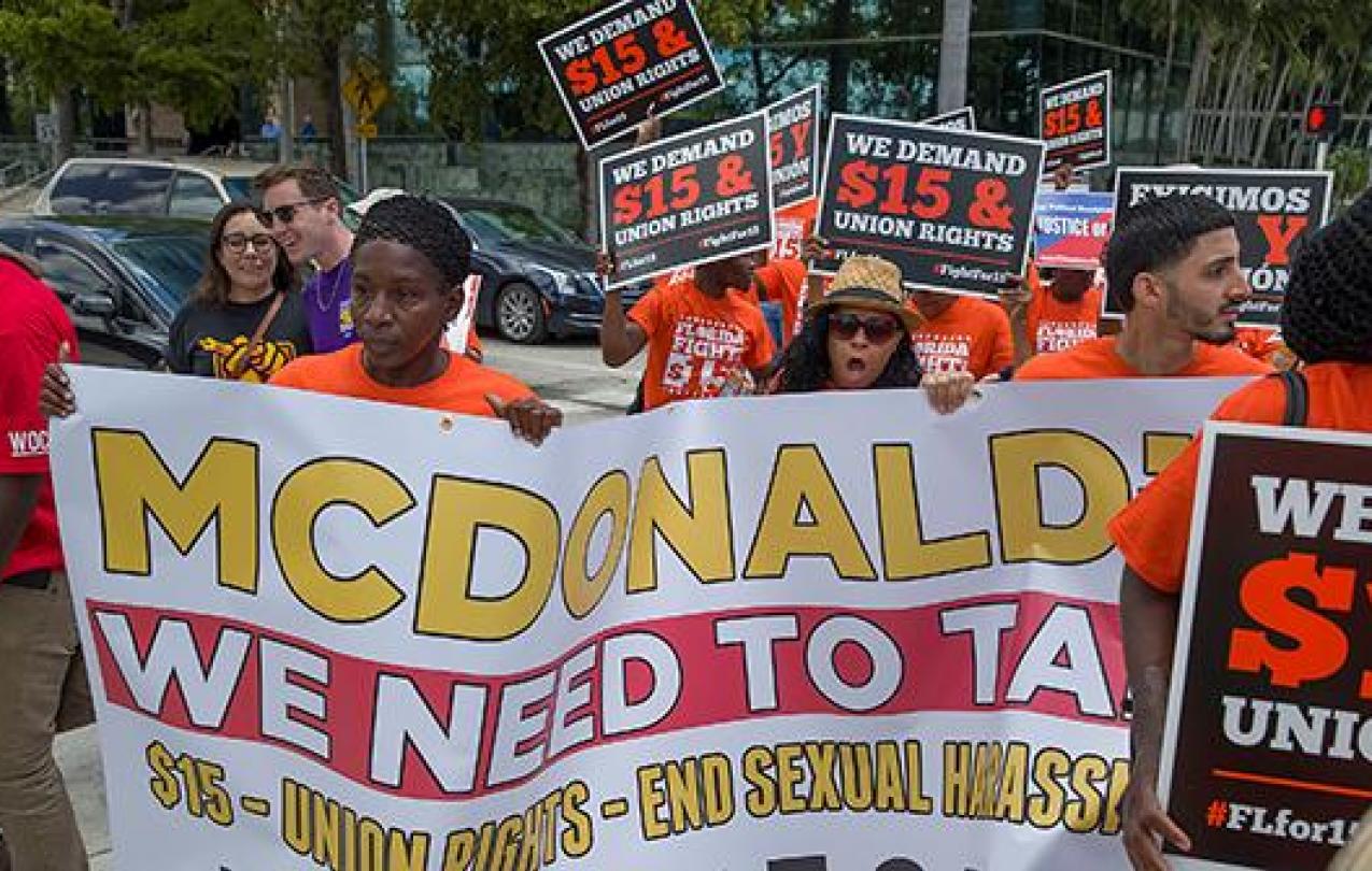 Supporters of the "Fight for $15" movement march with banners and posters.